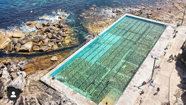 Une piscine en bord de mer, avec une eau claire, entourée d’un paysage rocheux et d’une plage.