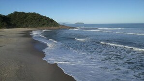 Ein Strand mit Wellen, ein bewaldeter Hügel und eine entfernte Insel.