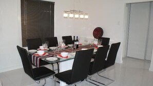 A dining area with a rectangular table set for six, black chairs, and a modern chandelier.