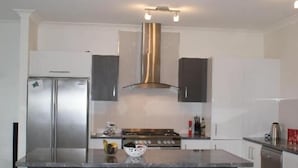 A modern kitchen with a central island, stainless steel appliances, and black bar stools.