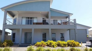 Stylish two-story residence with a flat roof and balcony, surrounded by a beautifully maintained garden.
