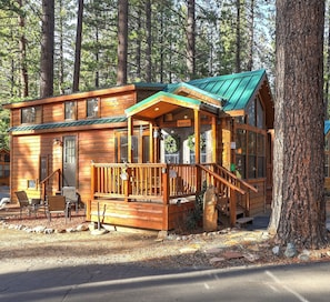 A wooden cabin with a porch, a staircase, and a sign welcoming guests.