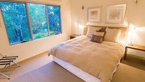 A bedroom with a large window, a bed with white bedding, two bedside tables with lamps, and two framed pictures on the wall. - Flutes Escape - Located on the exclusive Brookland Valley Vineyard property (Wilyabrup)