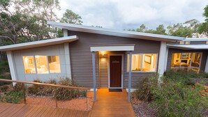 A modern house with a wooden deck, large windows, and a well-lit entrance. - Flutes Escape - Located on the exclusive Brookland Valley Vineyard property (Wilyabrup)
