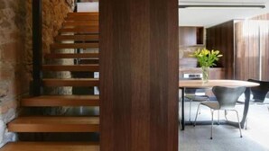 A staircase with wooden steps leading to a modern kitchen area with a dining table and chairs.