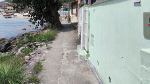 Un sentier côtier bordé d’un mur végétal, d’un arbre et d’un bâtiment doté d’un toit en tuiles.