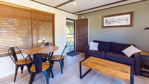 Ein modernes Wohnzimmer mit einem Holzesstisch, schwarzen Stühlen, einem dunklen Sofa und einem gerahmten Bild an der Wand.