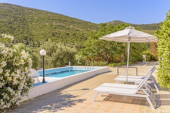 A swimming pool with lounge chairs and an umbrella, surrounded by greenery and hills. - House with character, private swimming pool, spectacular view (Samos)