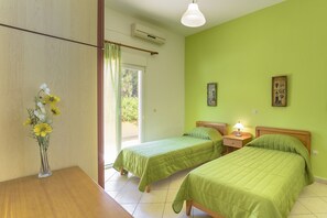 A room with two single beds, a wooden table, a vase with flowers, and a painting on the wall. - House with character, private swimming pool, spectacular view (Samos)