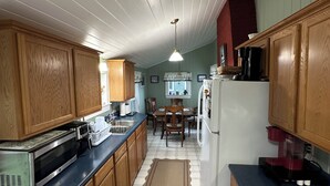 A kitchen with wooden cabinets, a microwave, a refrigerator, and a dining table with chairs.