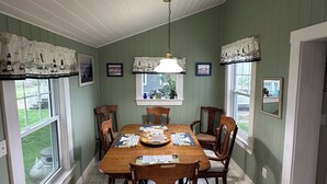 A dining room with a wooden table, chairs, a chandelier, and framed pictures on the walls.