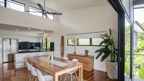 Een moderne keuken met een houten eettafel, witte stoelen en een groot raam.