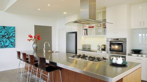 A modern kitchen with a central island, stainless steel appliances, and a bar area with stools.