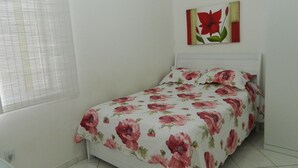 Ein Schlafzimmer mit Bett, einem Fenster mit Jalousien und einem Wandbild.