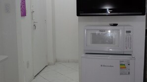 Ein Zimmer mit einer weißen Tür, einem wandmontierten Flachbildfernseher, einer Mikrowelle und einem Kühlschrank.