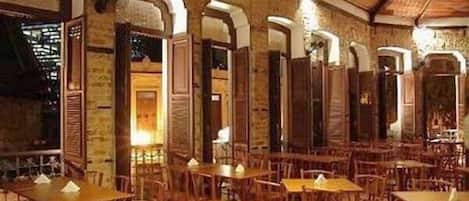 Un restaurante con mesas y sillas de madera, paredes de ladrillo y arcos.
