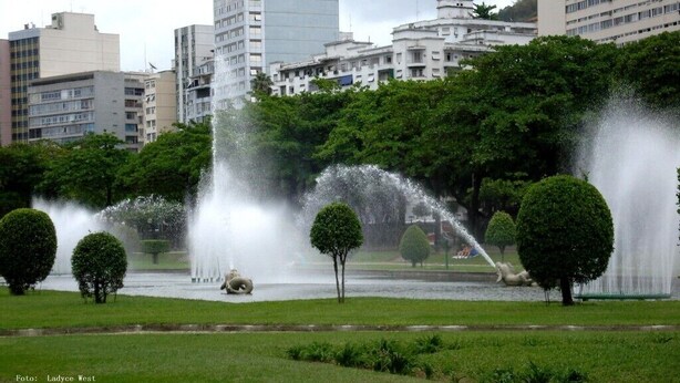 Ein Park mit Springbrunnen und Bäumen, umgeben von Gebäuden.