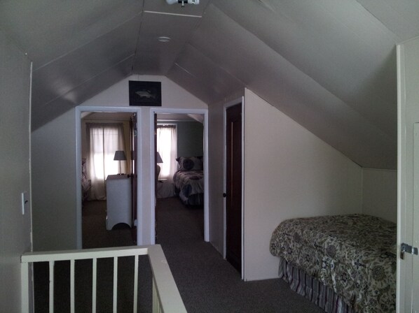 A bedroom with a bed, a nightstand, and a chair. There is a door leading to another room.