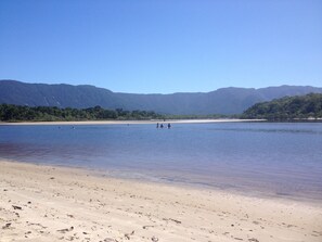 Uma praia com vista clara para o mar e montanhas ao longe.