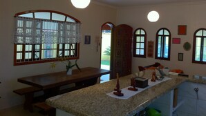 Cozinha com bancada de granito, armários de madeira e janela com cortina de renda.