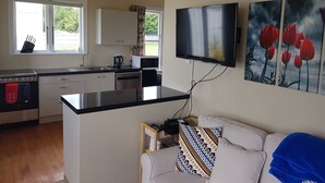 Una cocina moderna con televisor de pantalla plana, un área de comedor con sofá y obras de arte en la pared.