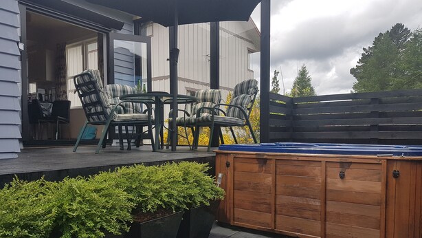 Un patio exterior con un jacuzzi, sillas y una mesa.