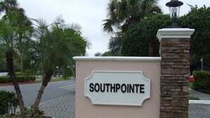 En skylt med namnet ”South Pointe” på en beige vägg, omgiven av palmer och en stenkantad pelare.