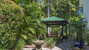 A garden with a gazebo, a stone pathway, and various plants.