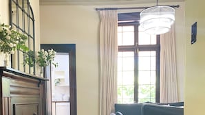 A living room with a sofa, a large green plant, a wooden cabinet, and a chandelier. - Oaklands Homestead (Pambula)