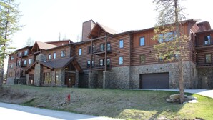 Un grand bâtiment de plusieurs étages, de style chalet, avec une façade en pierre et de nombreux balcons.
