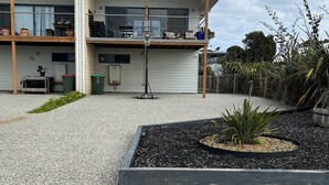 A two-story building with a balcony, a basketball hoop, and a garden area with pebbles and plants.