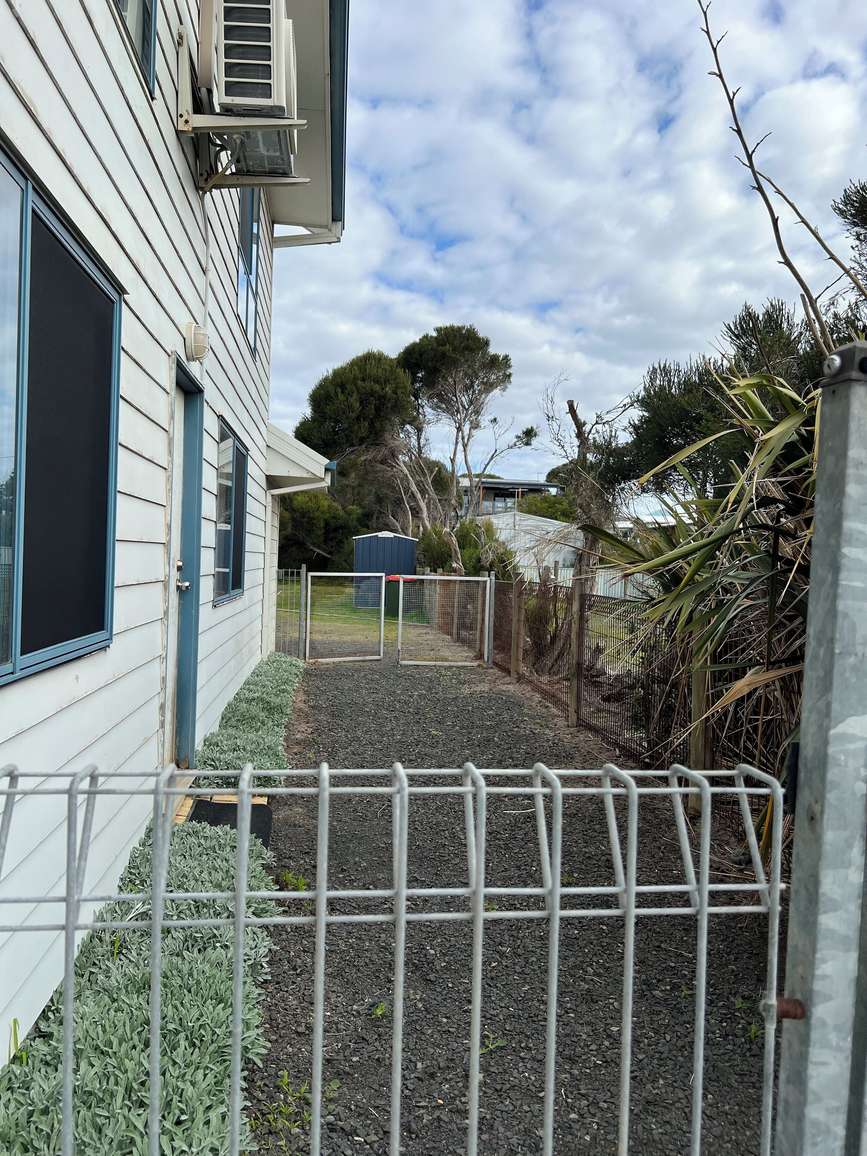 A residential property with a fenced yard, a small shed, and a large tree.