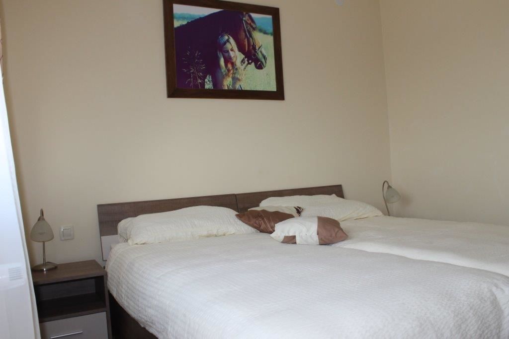 A bedroom with a bed, pillows, a nightstand, a lamp, and a framed picture on the wall.