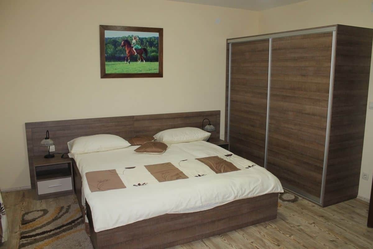 A bedroom with a bed, nightstands, a wardrobe, and a framed picture on the wall.