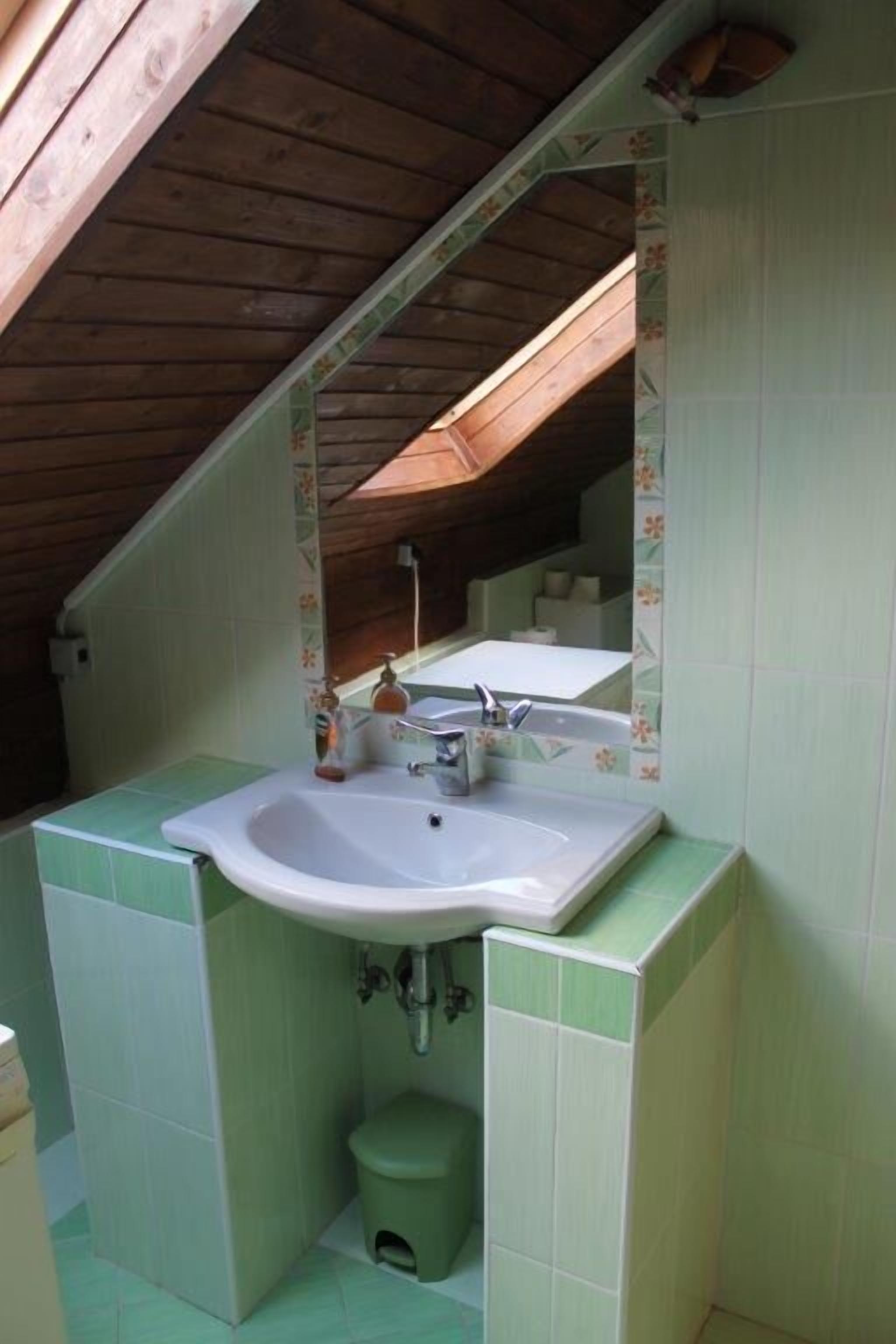 A small bathroom with a skylight, a sink, and a toilet.