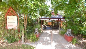 A pathway leading to a covered outdoor seating area with a signboard for Shambhala Retreat. - Shambhala Retreat Cottages a peaceful place intended for rest and relaxation. (Nelly Bay)