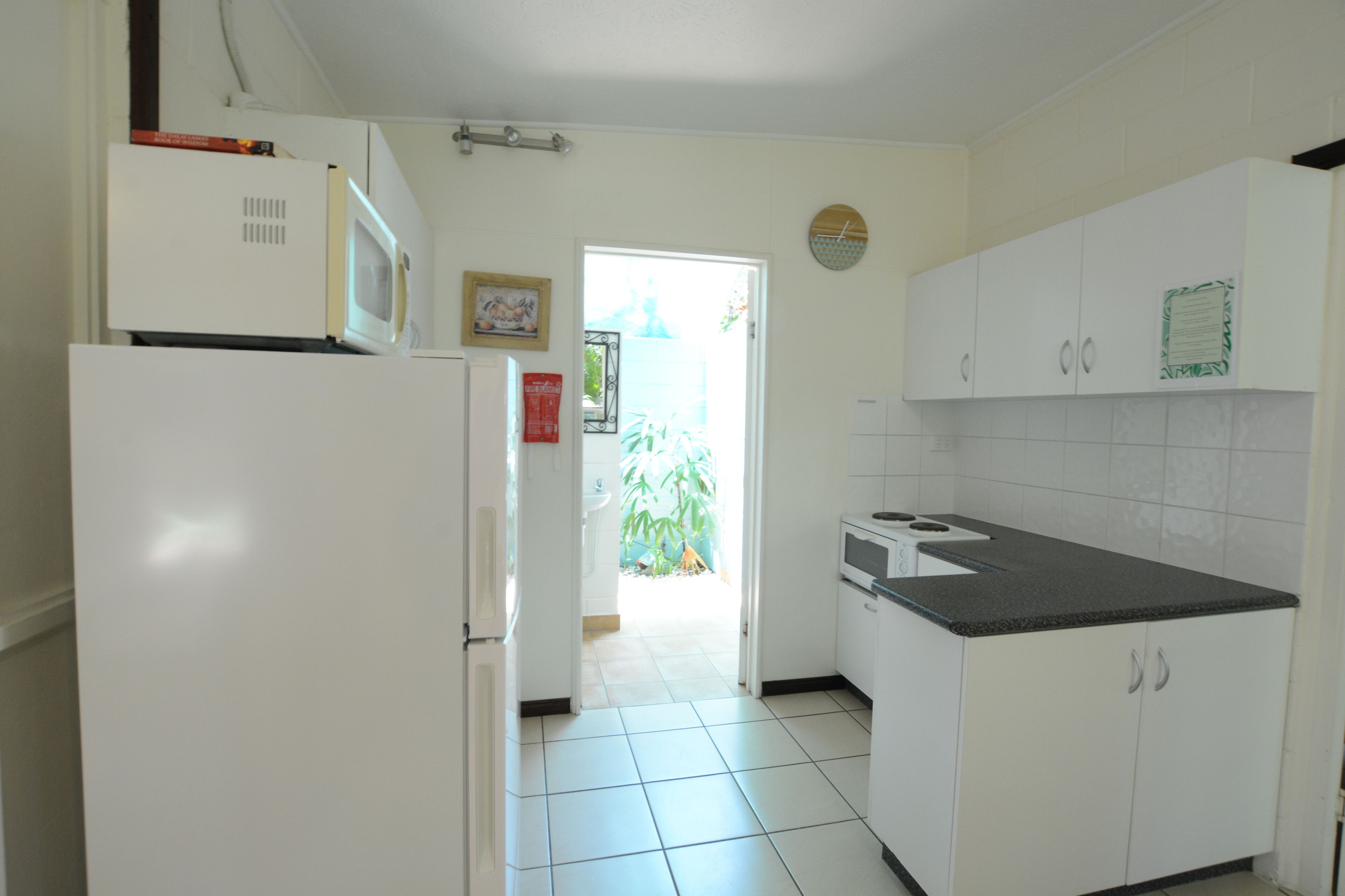A kitchen with white cabinets, a microwave, a stove, and a refrigerator.