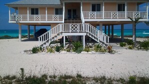 Una casa frente al mar de dos pisos, con un balcón y una escalera que lleva al nivel superior.