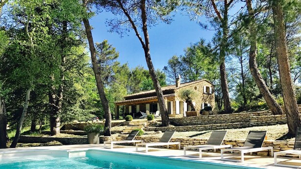 A pool area with lounge chairs and a stone building in the background.