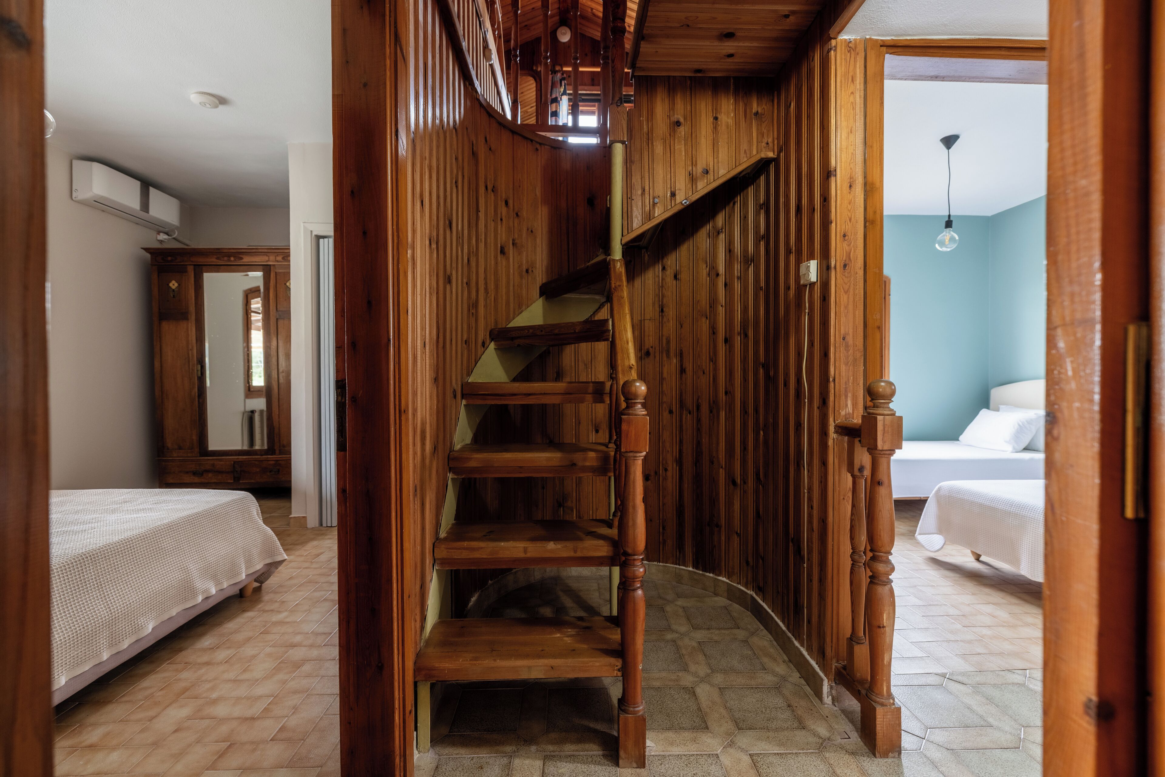 Una escalera de madera que conduce a un dormitorio con cama y mesita de noche.