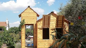 A wooden playhouse with a pitched roof and two windows. - Seafront cottage with orchard and garden (Drosia)