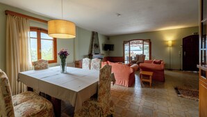 A dining area with a table, chairs, and a hanging light fixture. - Seafront cottage with orchard and garden (Drosia)