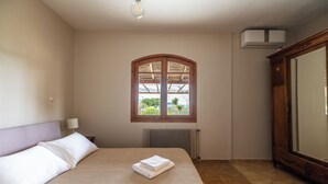 A bedroom with a bed, a window, a radiator, and a wardrobe. - Seafront cottage with orchard and garden (Drosia)