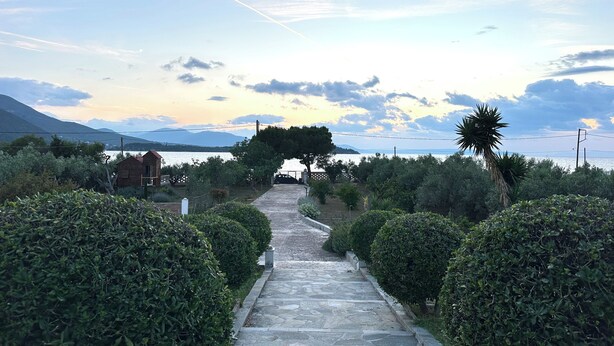 A stone pathway leading to a building with a view of the sea and mountains. - Seafront cottage with orchard and garden (Drosia)