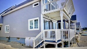 A two-story house with a balcony and a covered porch. - Beachfront 3-bedroom vacation home just 14 minutes from Yale University (Milford)