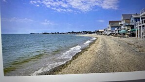 A beach with a sandy shore, a clear sky, and buildings along the coastline. - Beachfront 3-bedroom vacation home just 14 minutes from Yale University (Milford)