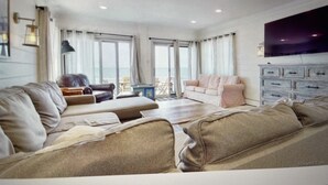 A spacious living room with a large sofa, a smaller sofa, and a TV mounted on the wall. - Beachfront 3-bedroom vacation home just 14 minutes from Yale University (Milford)
