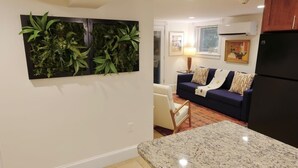Une cuisine dotée d’un plan de travail en granit, d’un réfrigérateur de couleur sombre et d’un présentoir à plantes fixé au mur.
