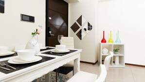 A dining area with a white table set for four, a dark brown door, and a white shelf with colorful vases. - Modern Building in City Center 3/2bath across Taipei Main Station (Taipei City)