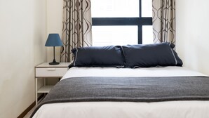 A hotel room with a bed, a nightstand, a lamp, and curtains. - Modern Building in City Center 3/2bath across Taipei Main Station (Taipei City)
